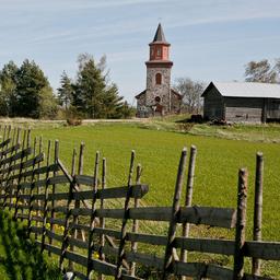Sofia Wilhelmina Church standing tall in a green field, marked with a wooden fence.